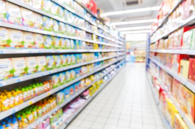 Renkli rafları ve tanınmayan müşterileri olan soyut bulanık süpermarket koridoru
