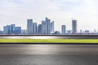 Panoramik siluet ve boş yolu, boş beton zemini olan modern iş binaları.