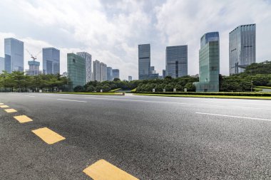 Panoramik siluet ve boş yolu, boş beton zemini olan modern iş binaları.