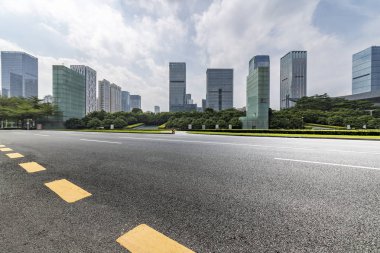 Panoramik siluet ve boş yolu, boş beton zemini olan modern iş binaları.