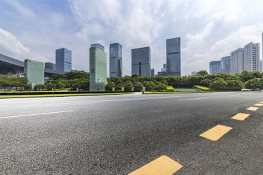 Panoramik siluet ve boş yolu, boş beton zemini olan modern iş binaları.