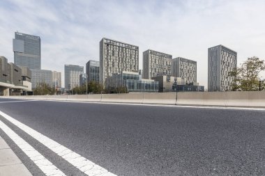 Panoramik siluet ve boş yolu, boş beton zemini olan modern iş binaları.