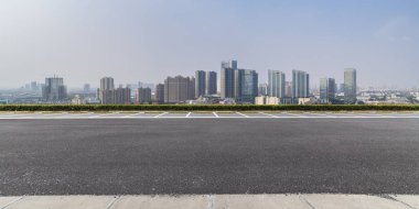 Panoramik siluet ve boş yolu, boş beton zemini olan modern iş binaları.