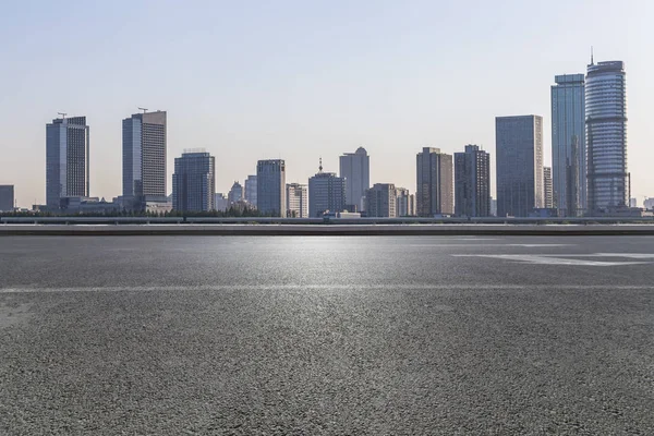 Panoramik siluet ve boş yolu, boş beton zemini olan modern iş binaları.