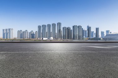 Panoramik siluet ve boş yolu, boş beton zemini olan modern iş binaları.