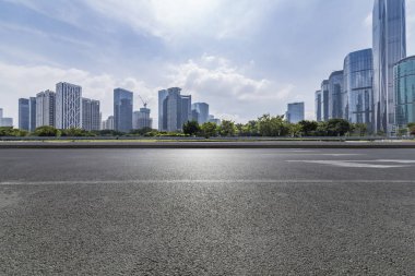Panoramik siluet ve boş yolu, boş beton zemini olan modern iş binaları.
