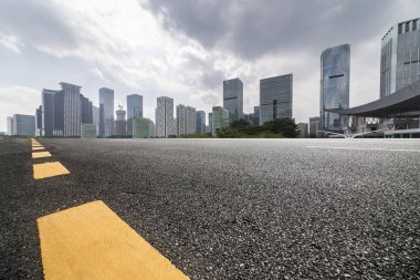 Panoramik siluet ve boş yolu, boş beton zemini olan modern iş binaları.