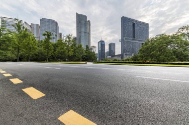 Panoramik siluet ve boş yolu, boş beton zemini olan modern iş binaları.