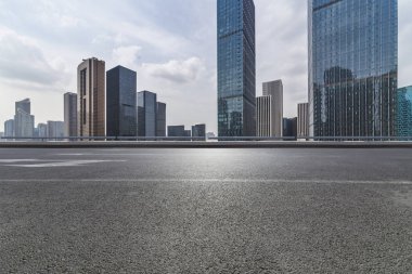 Panoramik siluet ve boş yolu, boş beton zemini olan modern iş binaları.