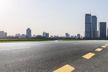 Panoramik siluet ve boş yolu, boş beton zemini olan modern iş binaları.
