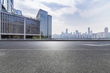 Panoramik siluet ve boş yolu, boş beton zemini olan modern iş binaları.