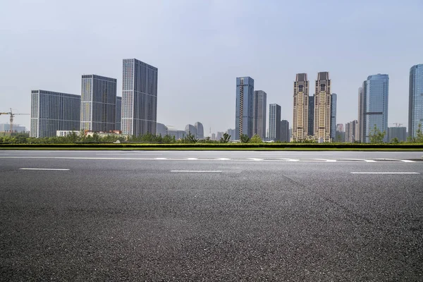 Panoramik siluet ve boş yolu, boş beton zemini olan modern iş binaları.