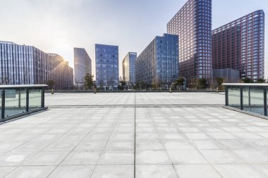 Panoramik siluet ve boş yolu, boş beton zemini olan modern iş binaları.