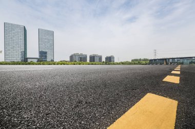 Panoramik siluet ve boş yolu, boş beton zemini olan modern iş binaları.