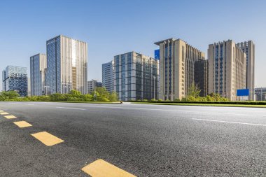 Panoramik siluet ve boş yolu, boş beton zemini olan modern iş binaları.