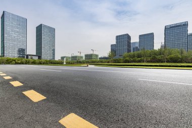 Panoramik siluet ve boş yolu, boş beton zemini olan modern iş binaları.