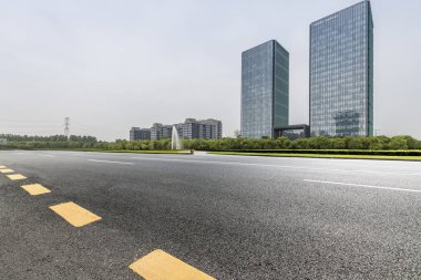 Panoramik siluet ve boş yolu, boş beton zemini olan modern iş binaları.
