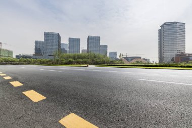 Panoramik siluet ve boş yolu, boş beton zemini olan modern iş binaları.