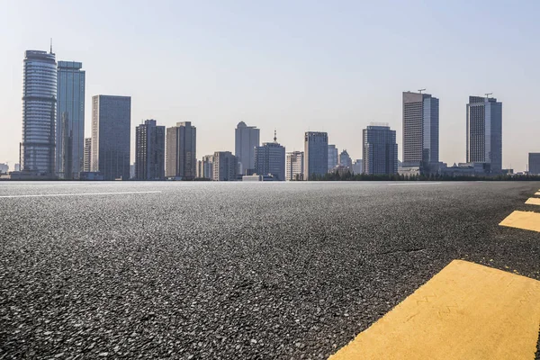 Panoramik siluet ve boş yolu, boş beton zemini olan modern iş binaları.