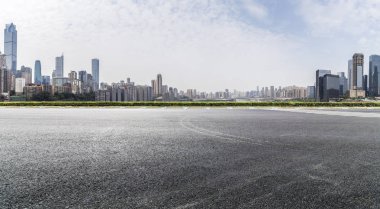 Panoramik siluet ve boş yolu, boş beton zemini olan modern iş binaları.