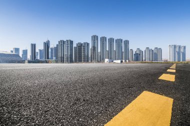 Panoramik siluet ve boş yolu, boş beton zemini olan modern iş binaları.