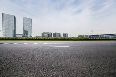 Panoramik siluet ve boş yolu, boş beton zemini olan modern iş binaları.