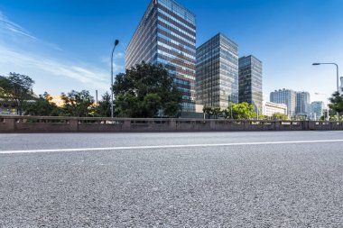 Panoramik siluet ve boş yolu, boş beton zemini olan modern iş binaları.