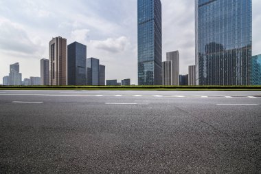 Panoramik siluet ve boş yolu, boş beton zemini olan modern iş binaları.