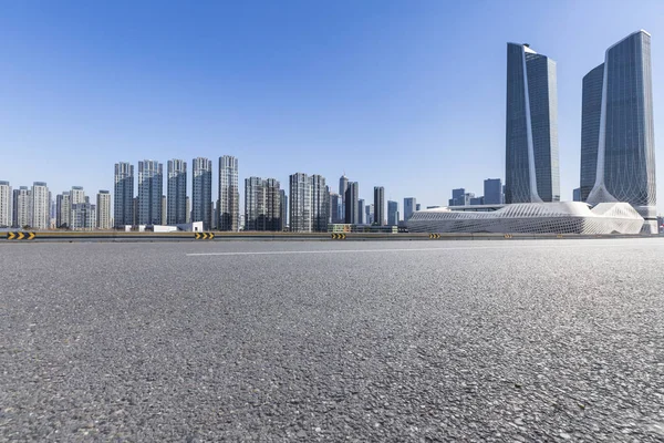 Panoramik siluet ve boş yolu, boş beton zemini olan modern iş binaları.