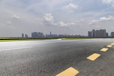 Panoramik siluet ve boş yolu, boş beton zemini olan modern iş binaları.