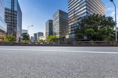 Panoramik siluet ve boş yolu, boş beton zemini olan modern iş binaları.