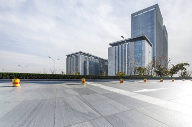 Panoramik siluet ve boş yolu, boş beton zemini olan modern iş binaları.
