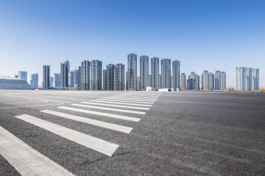 Panoramik siluet ve boş yolu, boş beton zemini olan modern iş binaları.