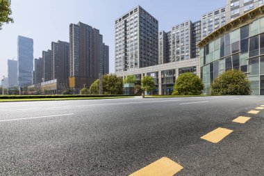 Panoramik siluet ve boş yolu, boş beton zemini olan modern iş binaları.