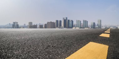Panoramik siluet ve boş yolu, boş beton zemini olan modern iş binaları.