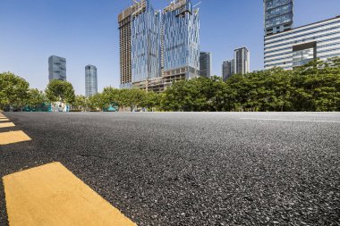 Panoramik siluet ve boş yolu, boş beton zemini olan modern iş binaları.