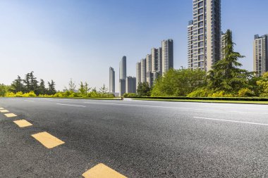 Panoramik siluet ve boş yolu, boş beton zemini olan modern iş binaları.
