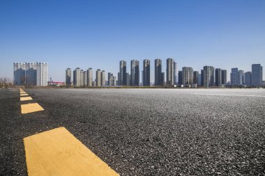 Panoramik siluet ve boş yolu, boş beton zemini olan modern iş binaları.