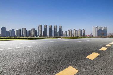 Panoramik siluet ve boş yolu, boş beton zemini olan modern iş binaları.