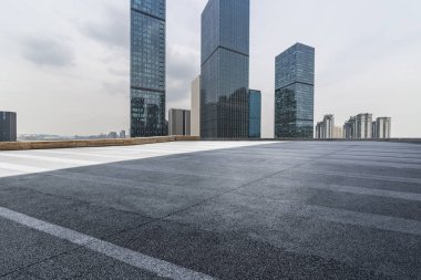 Panoramik siluet ve boş yolu, boş beton zemini olan modern iş binaları.