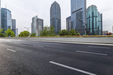 Panoramik siluet ve boş yolu, boş beton zemini olan modern iş binaları.