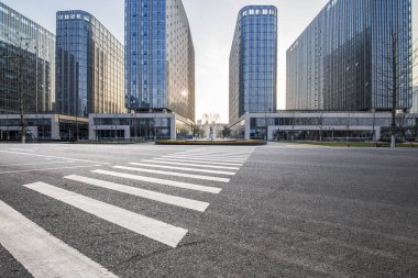 Panoramik siluet ve boş yolu, boş beton zemini olan modern iş binaları.