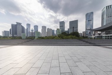 Panoramik siluet ve boş yolu, boş beton zemini olan modern iş binaları.
