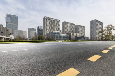 Panoramik siluet ve boş yolu, boş beton zemini olan modern iş binaları.