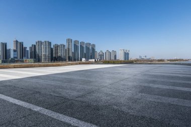 Panoramik siluet ve boş yolu, boş beton zemini olan modern iş binaları.