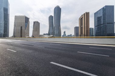 Panoramik siluet ve boş yolu, boş beton zemini olan modern iş binaları.