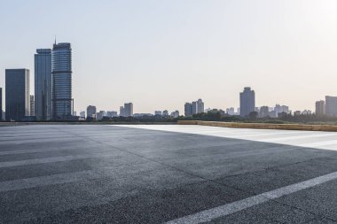 Panoramik siluet ve boş yolu, boş beton zemini olan modern iş binaları.