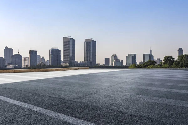 Panoramik siluet ve boş yolu, boş beton zemini olan modern iş binaları.