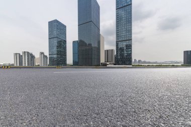 Panoramik siluet ve boş yolu, boş beton zemini olan modern iş binaları.