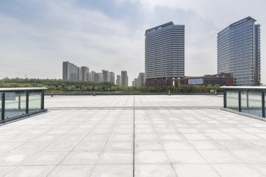 Panoramik siluet ve boş yolu, boş beton zemini olan modern iş binaları.